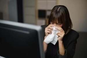 Woman at desk with tissue.